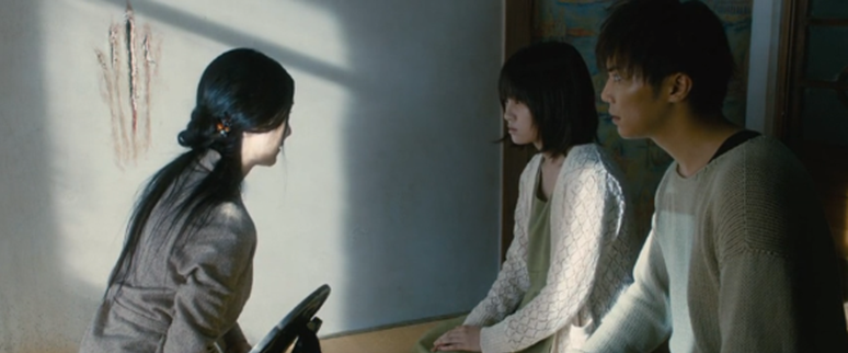 La médium con Asuka y Shinobu en la casa del vecino frente a las marcas de uñas en la pared.
