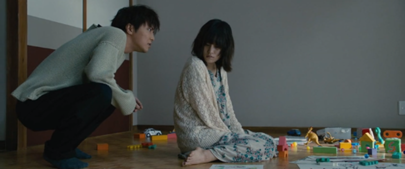 La tonalidad gris contrasta con el color vivo de los juguetes esparcidos por el suelo. Asuka asume el papel de madre y hermana de Minoru, única alegría en su vida de soledad.